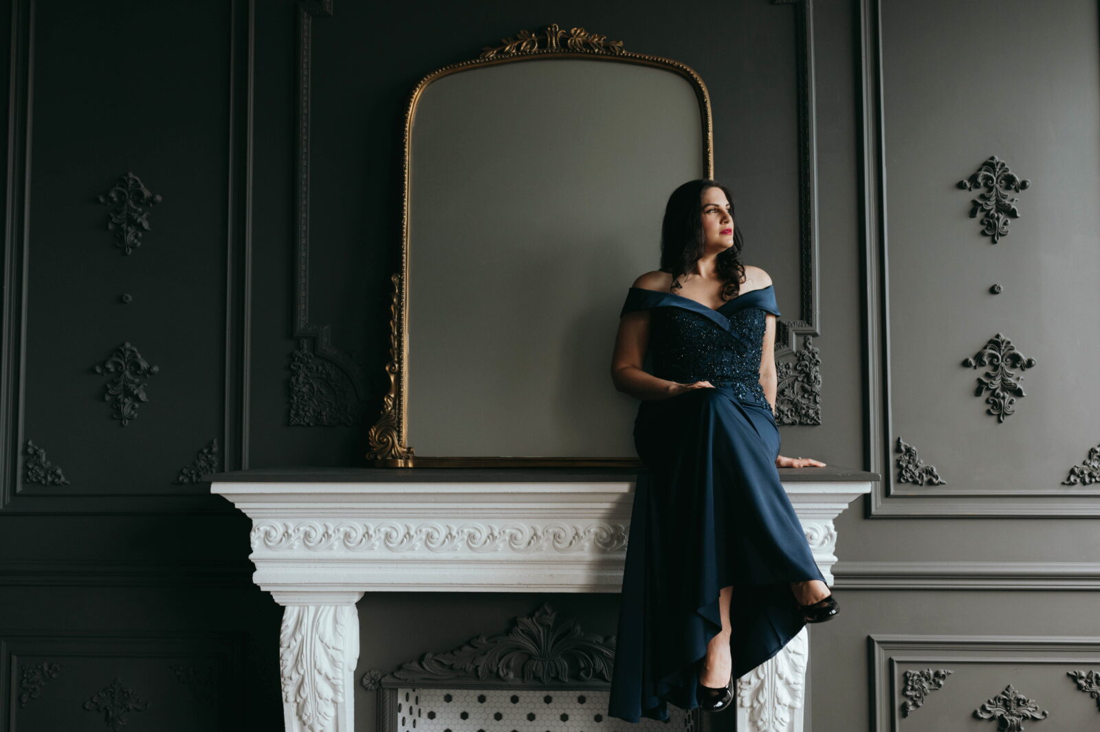 Stephanie DeCiantis in a navy gown beside an ornate mirror